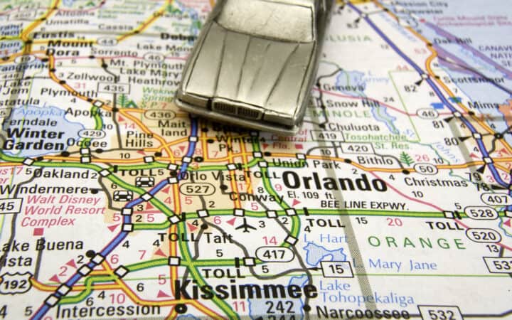 Close-up of a silver model car atop a map of Florida, pointing toward Orlando and Disney World.